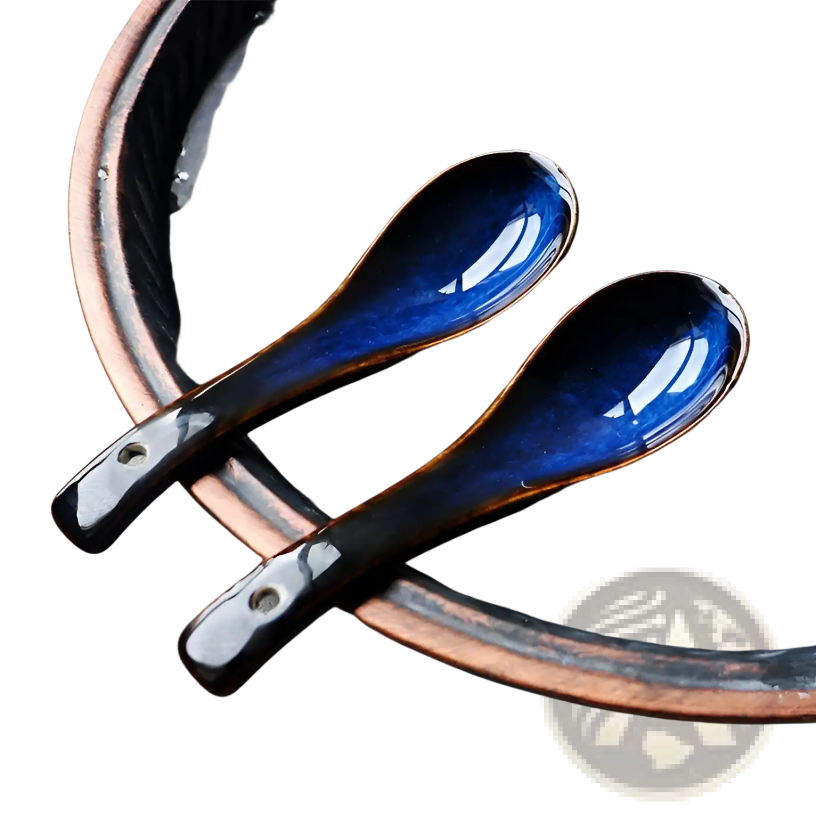 Two glossy cobalt blue kiln glaze ceramic spoons with dark brown handles rest on a copper-rimmed plate for tableware use