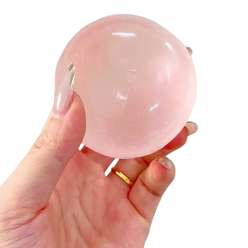 A translucent pink spherical gel ball held in a hand for the blue coconut oil stress relief squeeze ball product