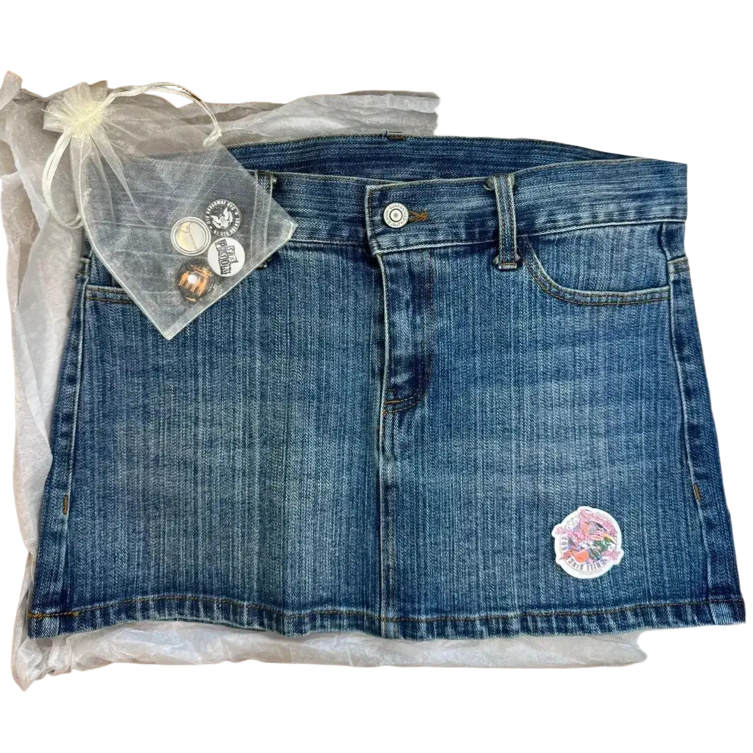 A medium-wash blue denim mini skirt with high waist front buttons and colorful embroidered patch for Y2K streetwear