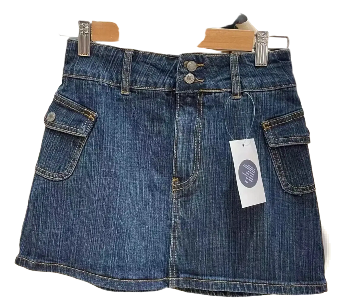A dark blue denim mini skirt with high waist button closure and two front pockets hanging on a wooden hanger