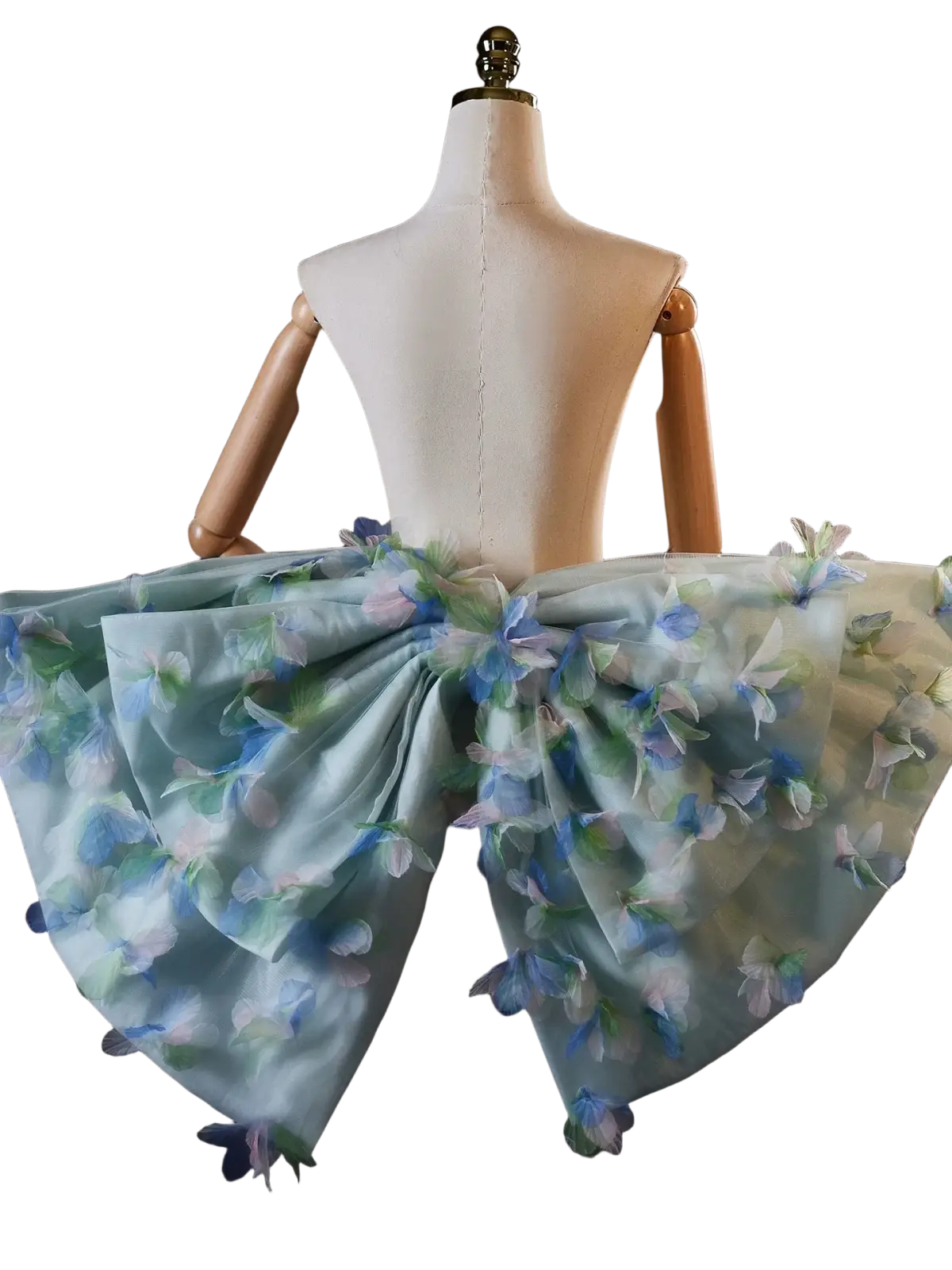A delicate light blue floral bridal bow evening party skirt with sheer fabric and embroidered blossoms on a mannequin