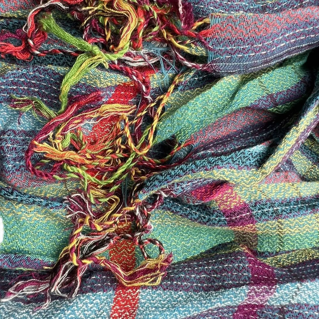A vibrant multicolored blue jacquard textured winter scarf with plaid pattern and frayed edges for cold weather use