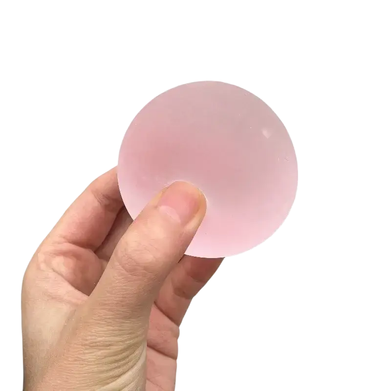 A translucent pink silicone stress ball held in hand from the blue mochi squeeze sensory fidget toy collection