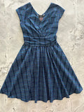 A navy blue and teal plaid cotton dress with v-neckline, short sleeves, gathered waist, and pockets