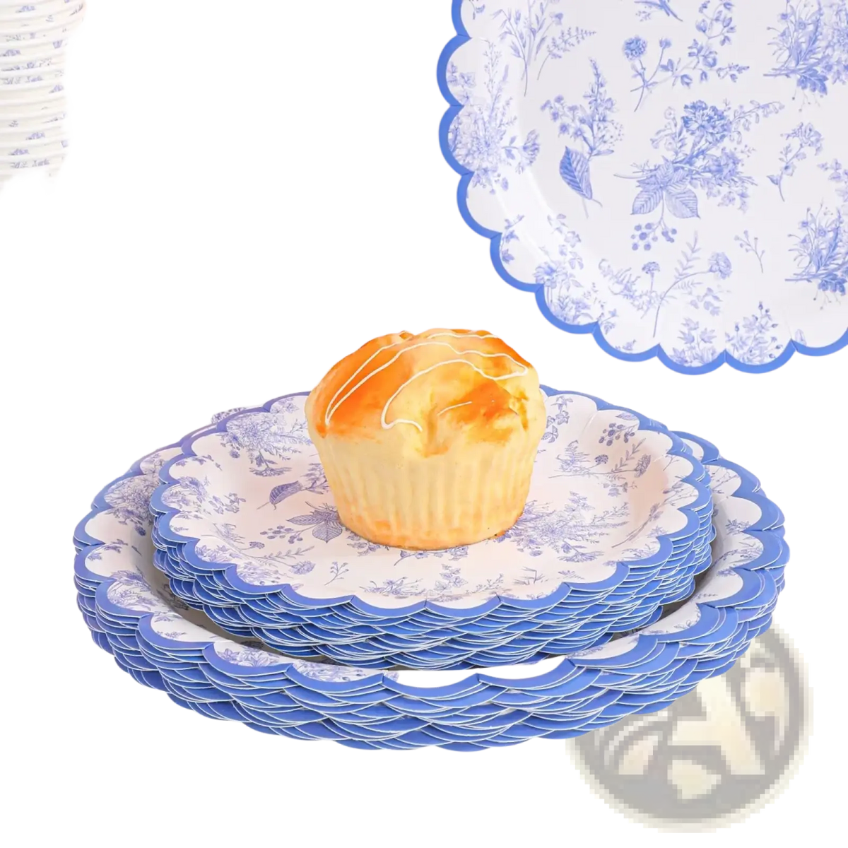 A golden-brown cupcake with white icing on a stack of blue and white floral porcelain party tableware plates