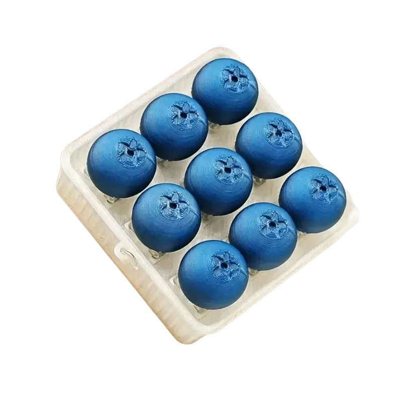 Nine glossy blue spherical blueberry fidget toy buttons with embossed floral patterns in a white egg carton for stress relief