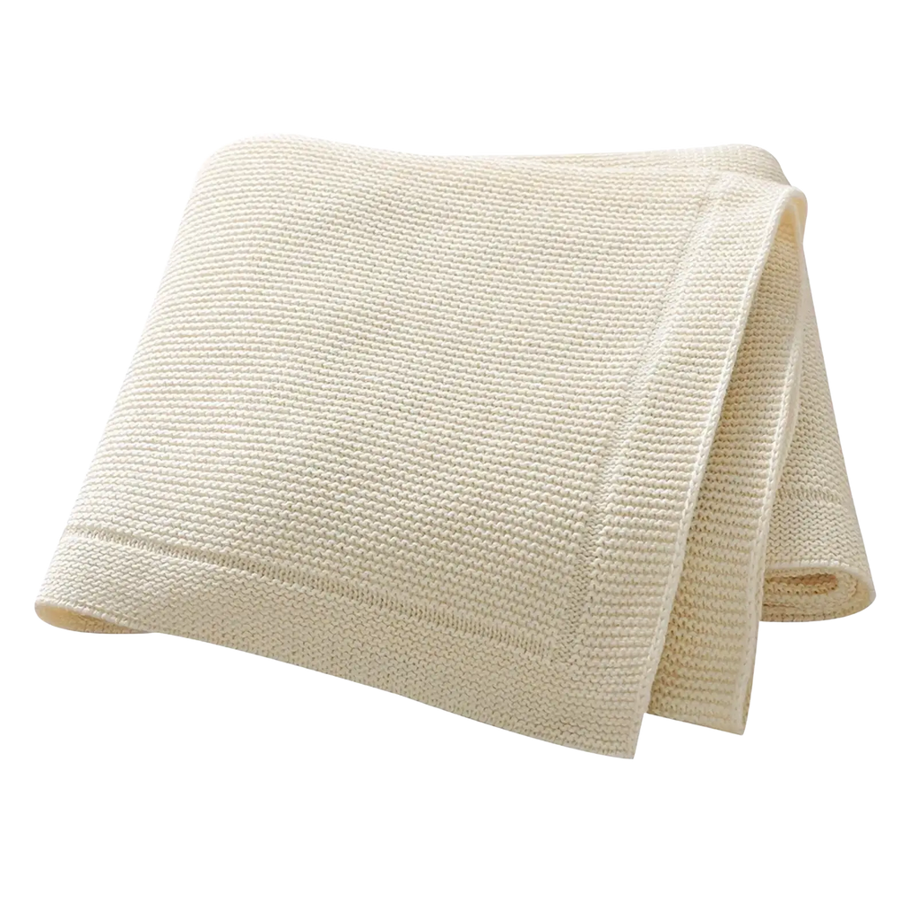 Cream-colored waffle-weave towel with soft texture and finished edges paired with blush pink knitted cotton baby blanket