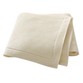 Cream-colored waffle-weave towel with soft texture and finished edges paired with blush pink knitted cotton baby blanket