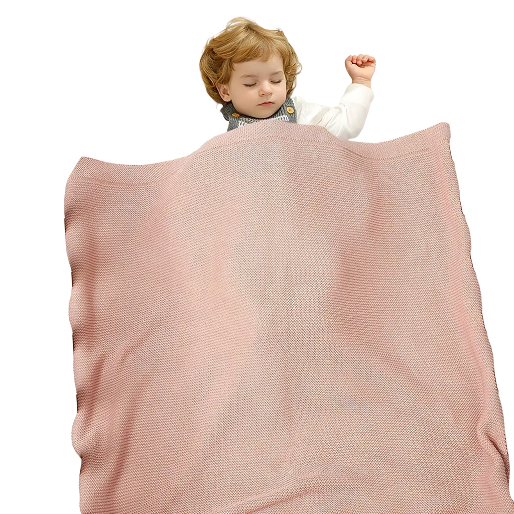 Soft pink knitted baby blanket with textured weave draped over a sleeping child in a crib for cotton receiving