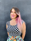 A woman wears a vintage 1950s black and white checkered boat neck top paired with a colorful halloween print skirt