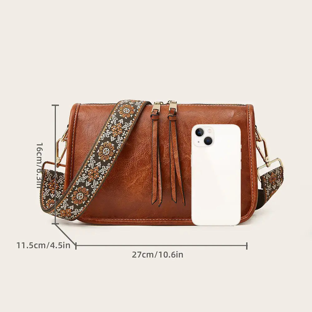Brown faux leather crossbody bag with aztec embroidered patterned wide strap and tassel details for bohemian style