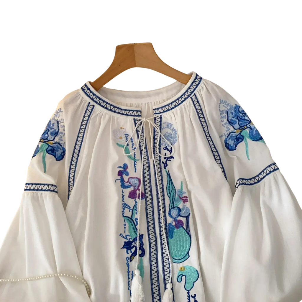 White cotton boho embroidered blouse with blue and purple floral embroidery decorative geometric trim and front drawstring closure