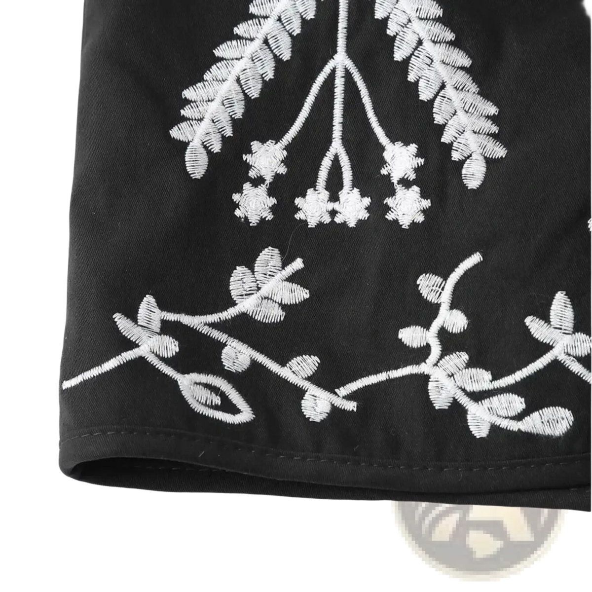 Black denim shorts with intricate white floral embroidery along the hem complementing boho floral embroidered quilted vest