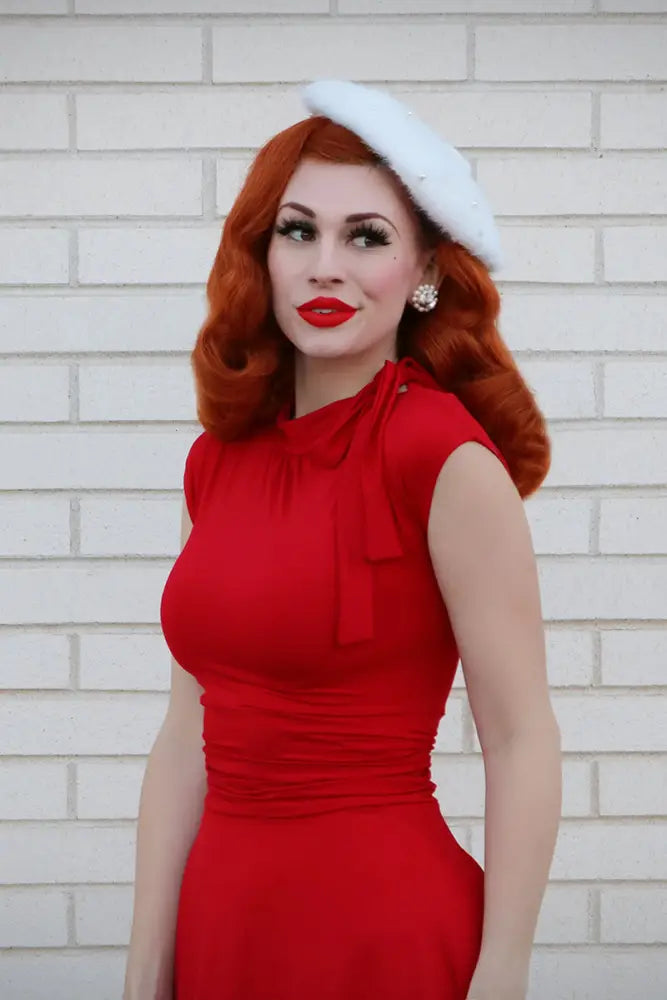 A vibrant red retro plus size sleeveless fitted dress with ruched bodice bow neckline and pockets