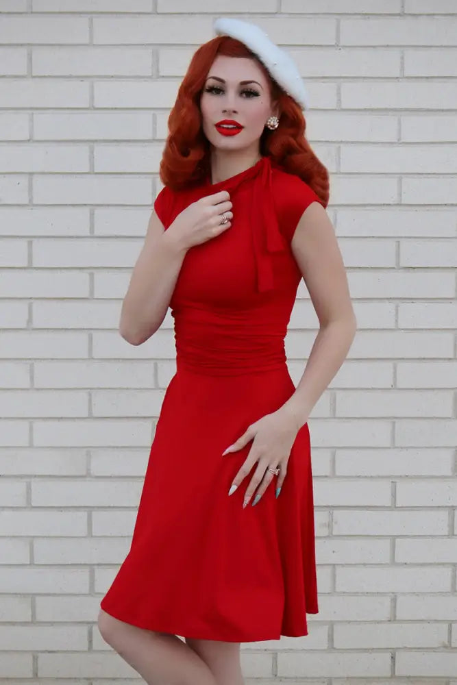 A vibrant red sleeveless fitted plus size bombshell dress with ruched waist flared skirt and pockets