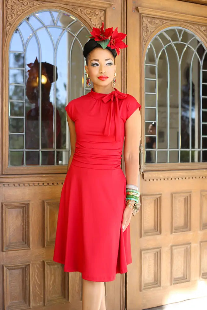 A vibrant red retro plus size bombshell dress with short sleeves high neckline and bow collar with pockets