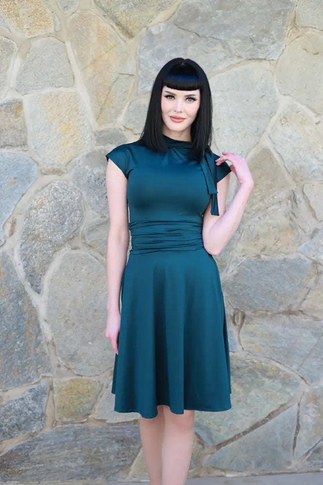 A spruce green bombshell satin sleeveless retro flare dress with a fitted bodice ruched waistband and flared skirt