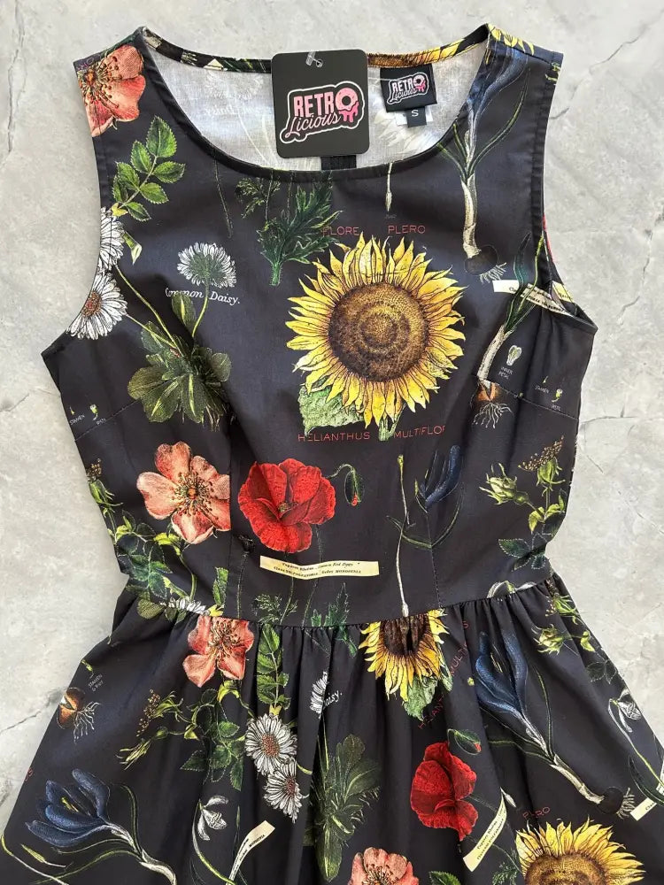 A black sleeveless cotton dress with vibrant sunflower and red poppy botanical print and pockets