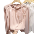 A soft blush pink satin bow chiffon blouse with long sleeves and a delicate sheer bow neckline for elegant office wear
