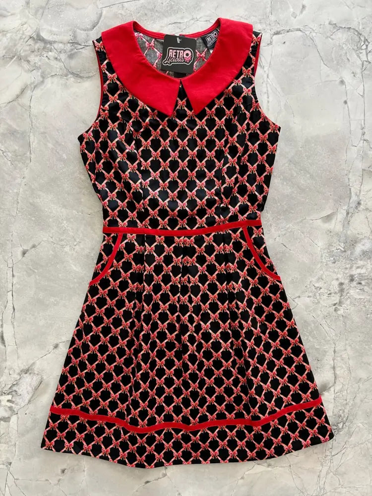 A sleeveless black and red retro bow print cotton a-line dress with a bold red peter pan collar trim