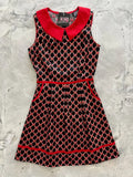 A sleeveless black and red retro bow print cotton a-line dress with a bold red peter pan collar trim
