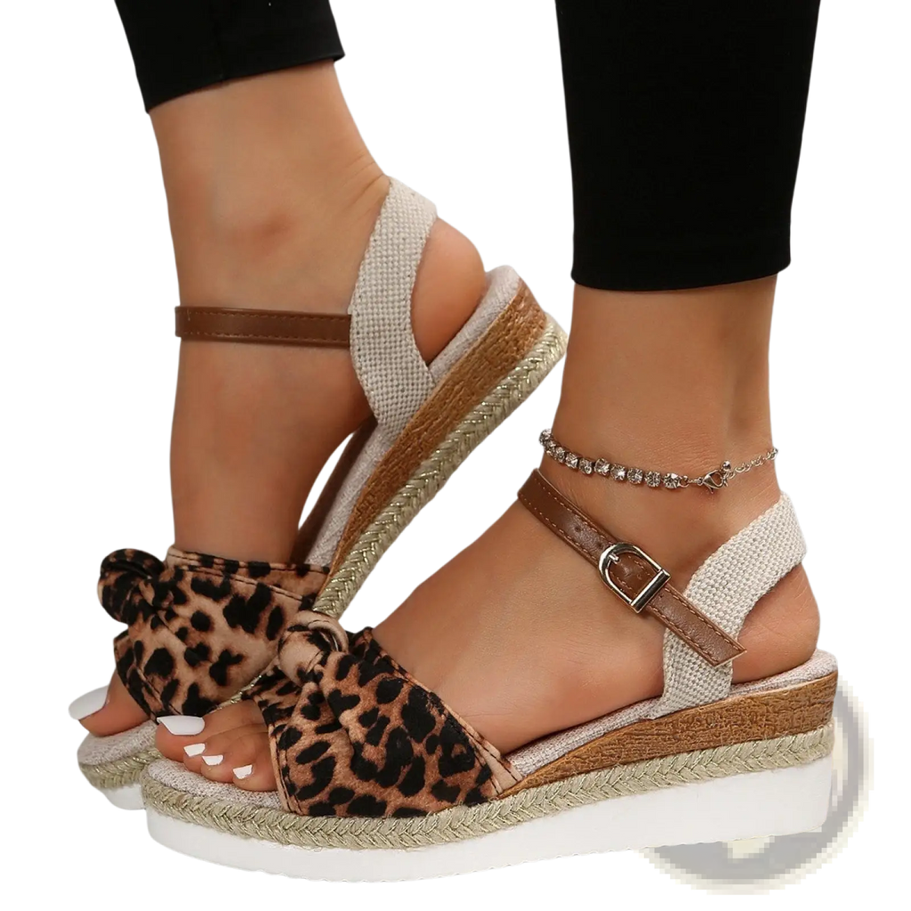 Bow wedge sandals with leopard print, woven rope espadrille sole, and brown leather buckle strap shown from the back