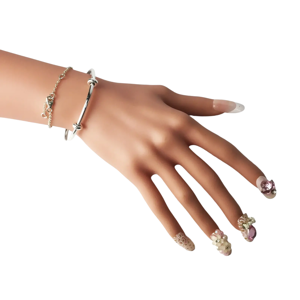 A hand with intricate pink and gold nails wearing a silver bracelet bangles classic open cuff in bangles classic design