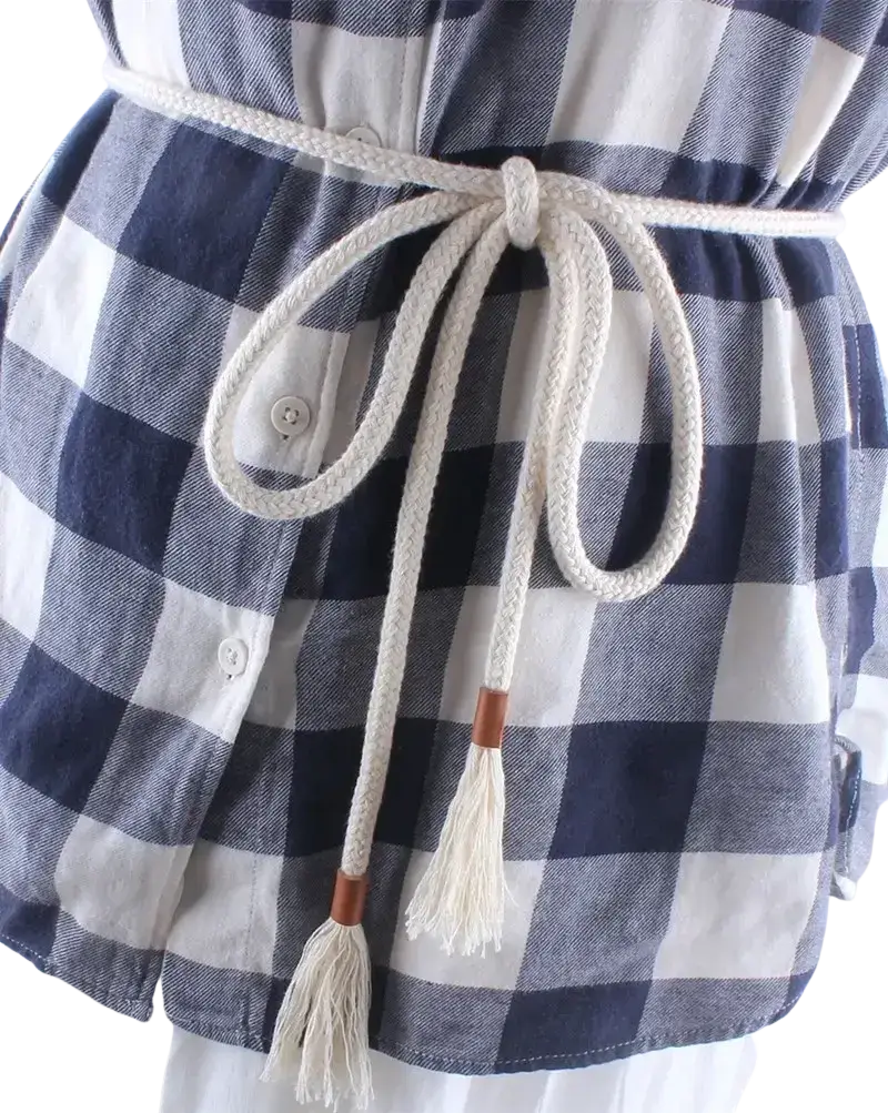 A cream-colored braided rope belt with wooden toggle ends and tassels worn over a navy and white plaid shirt