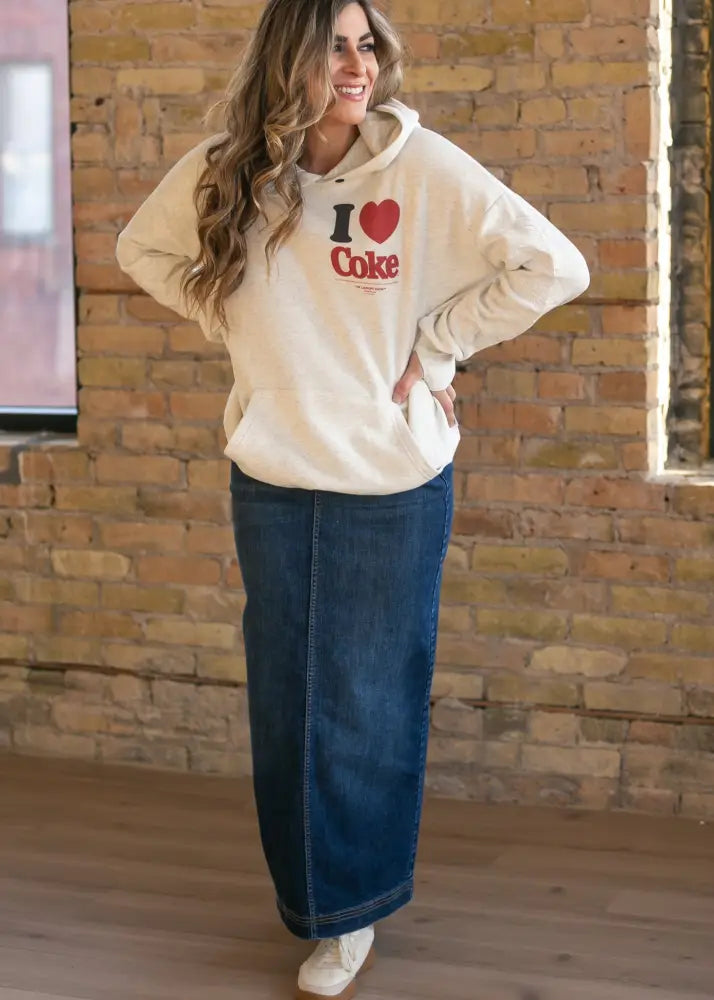 Cream-colored hoodie with i heart coke graphic in red and black paired with bria dark wash denim maxi skirt with side slit