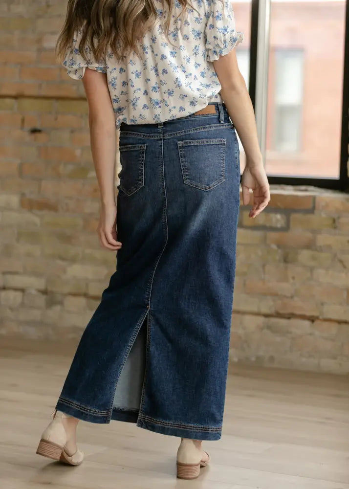 Dark blue denim maxi skirt with front slit and classic back pockets shown from the back side