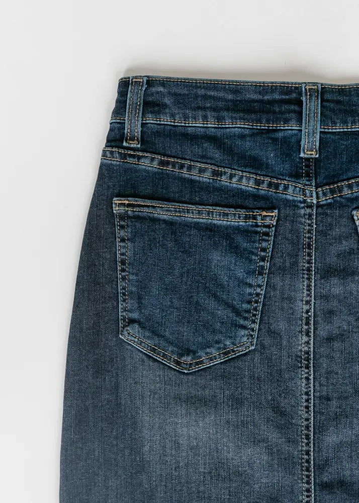 Back view of bria dark wash denim maxi skirt with side slit featuring classic pocket and visible stitching
