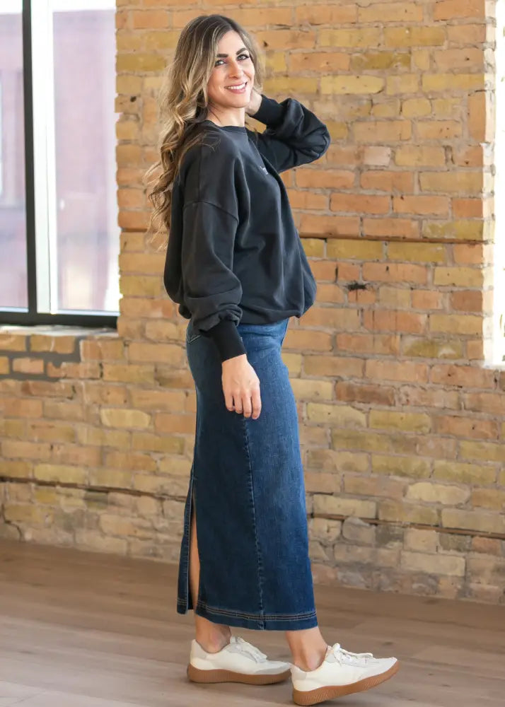 Dark gray oversized sweatshirt with black ribbed cuffs paired with Bria dark wash denim maxi skirt with side slit