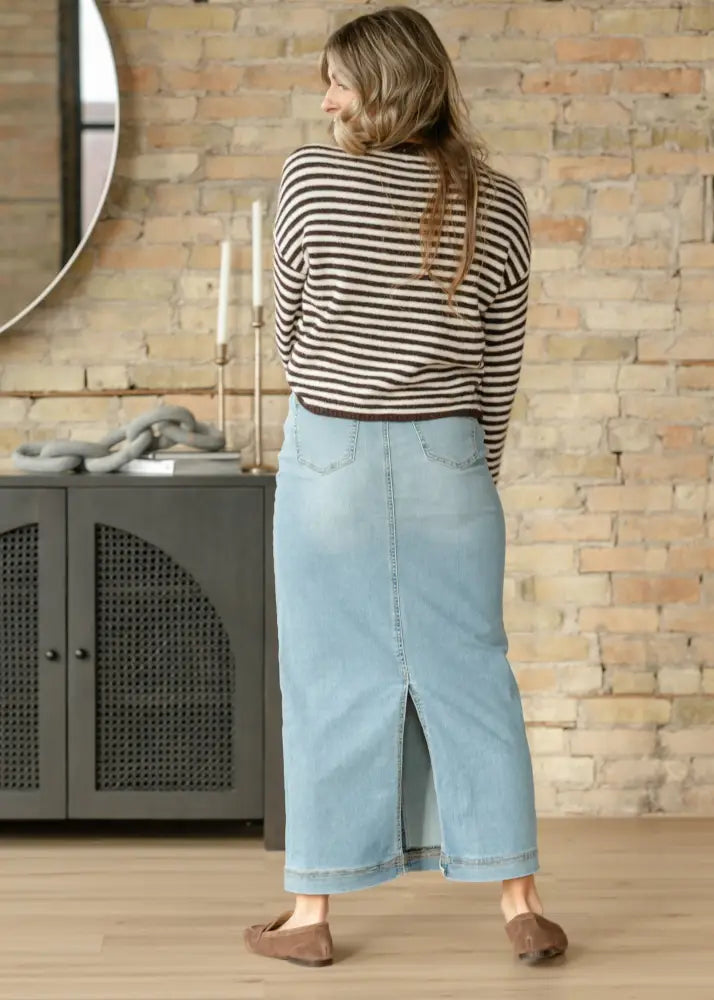 Bria light wash sustainable denim midi skirt in light blue with front slit and back pockets shown from the back side