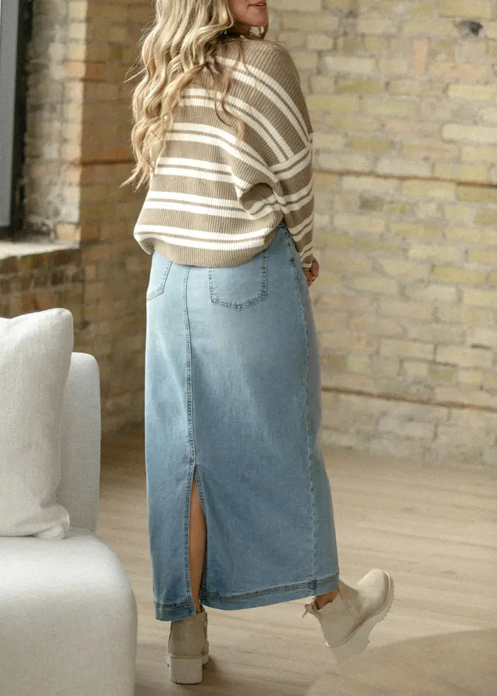 Bria light wash sustainable denim midi skirt in light blue with a front slit and back pockets shown from the back side