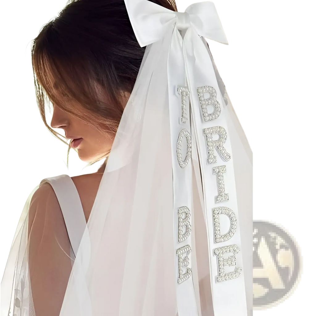 A delicate white satin bridal bow veil adorned with sparkling rhinestone bride lettering along its length