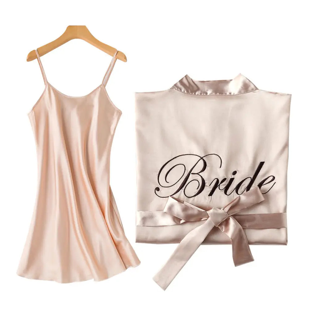 A blush pink satin bridesmaid robe with black cursive bride inscription and matching ribbon tie from embroidered satin bridal set