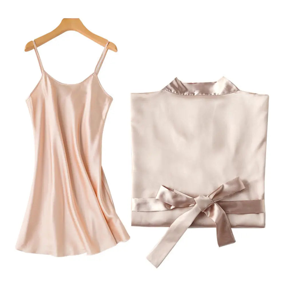 A delicate blush pink embroidered satin bridal nightgown with thin straps and matching satin robe tied at the waist