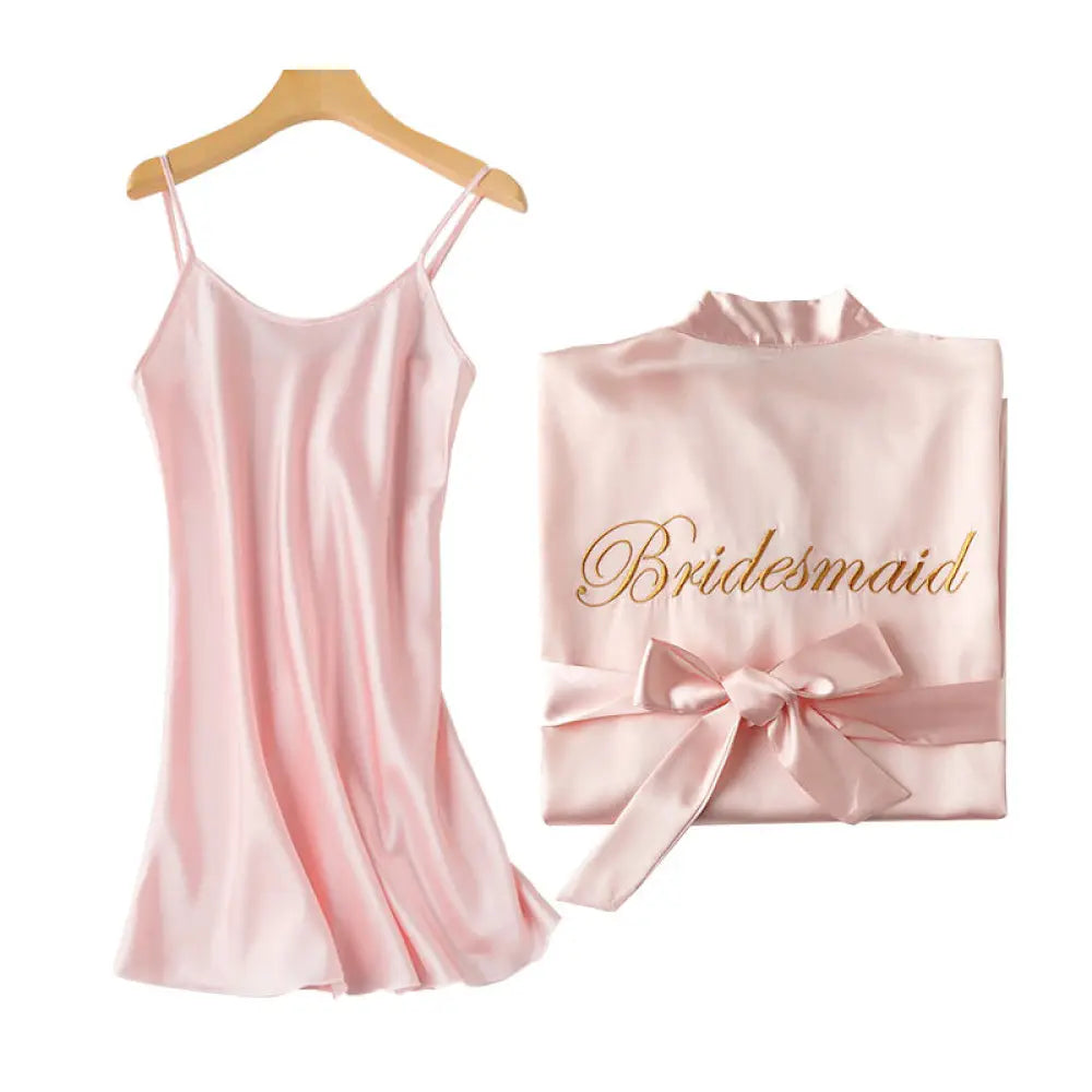A soft pink satin bridesmaid robe with gold cursive lettering and matching ribbon bow from embroidered satin bridal nightgown and robe set