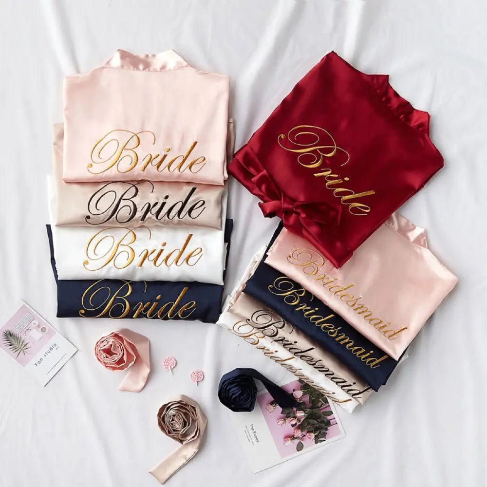 A collection of embroidered satin bridal nightgown and robe sets in soft pink white navy blue and deep red with gold lettering