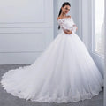 A white off-the-shoulder lace wedding gown with long sleeves and a voluminous tulle skirt with long train