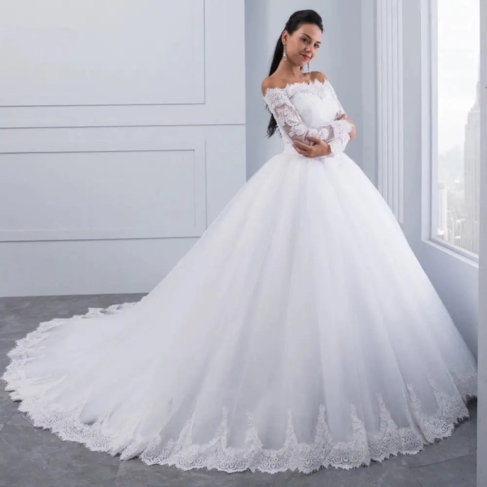 A white off-the-shoulder lace wedding gown with long sleeves and a voluminous tulle skirt with long train