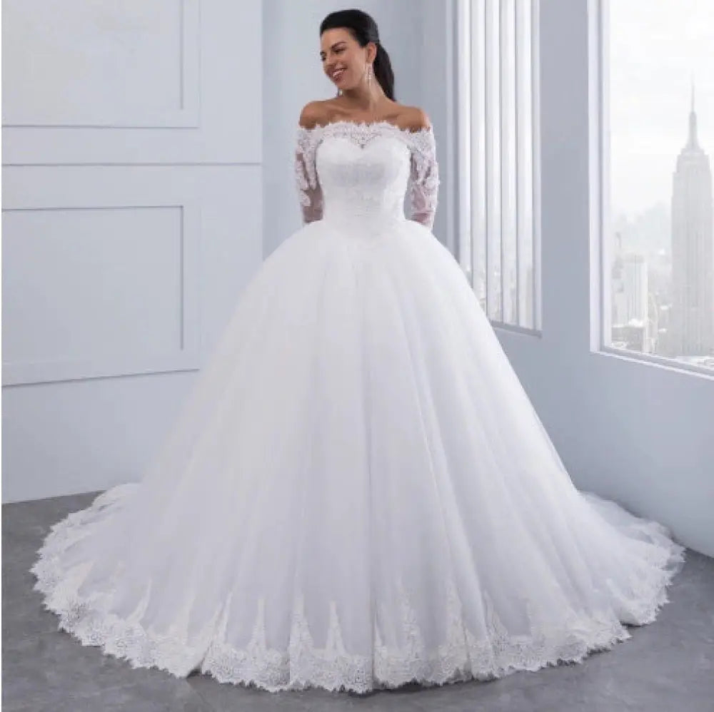 White off-the-shoulder lace wedding gown with long sleeves and a voluminous tulle skirt with long train