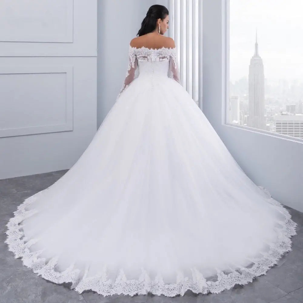 A white off-the-shoulder lace wedding gown with long sheer sleeves and intricate detailing along the neckline and hemline