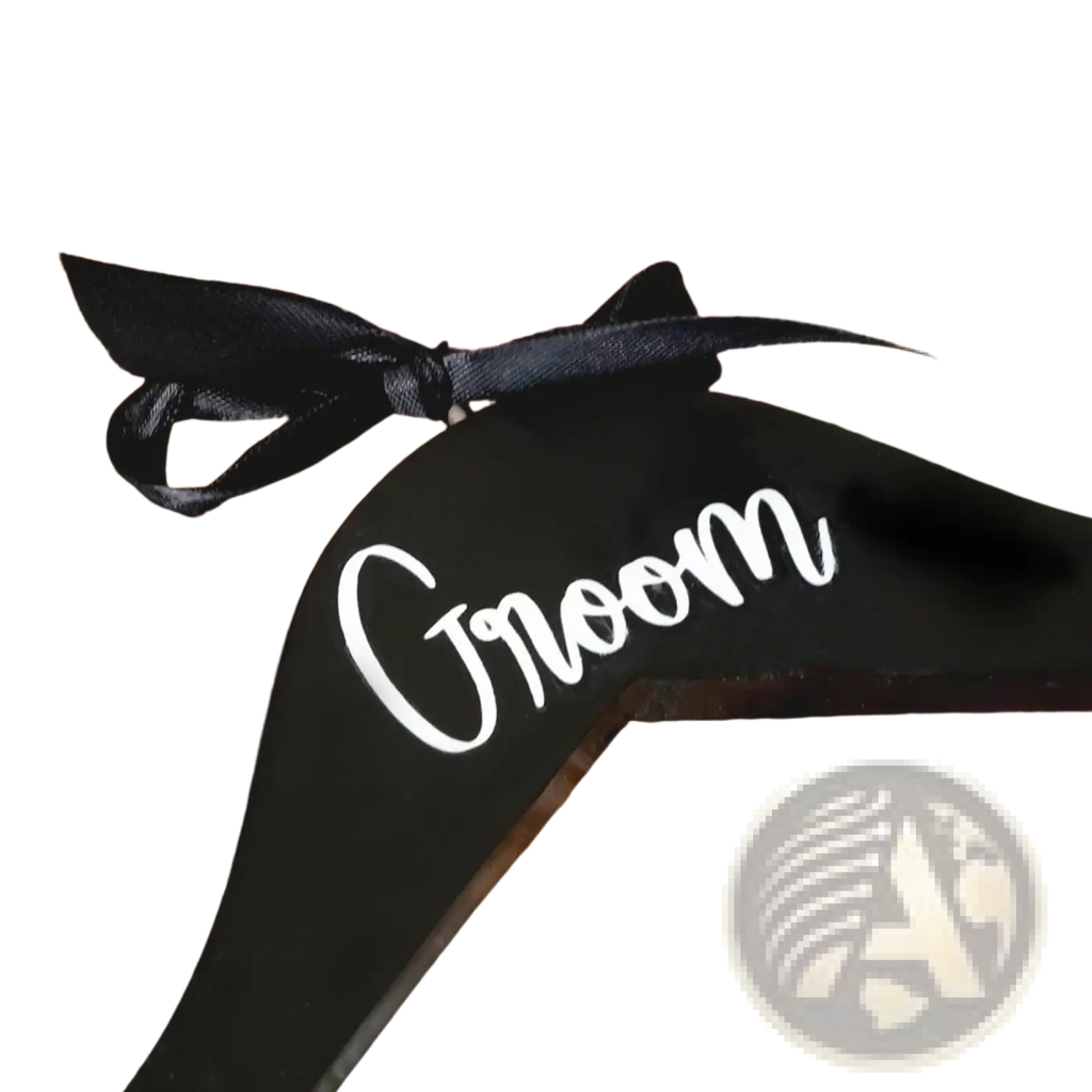 Black wooden groom hanger with white cursive script and black satin ribbon bow from bride and groom pearl wedding hangers set