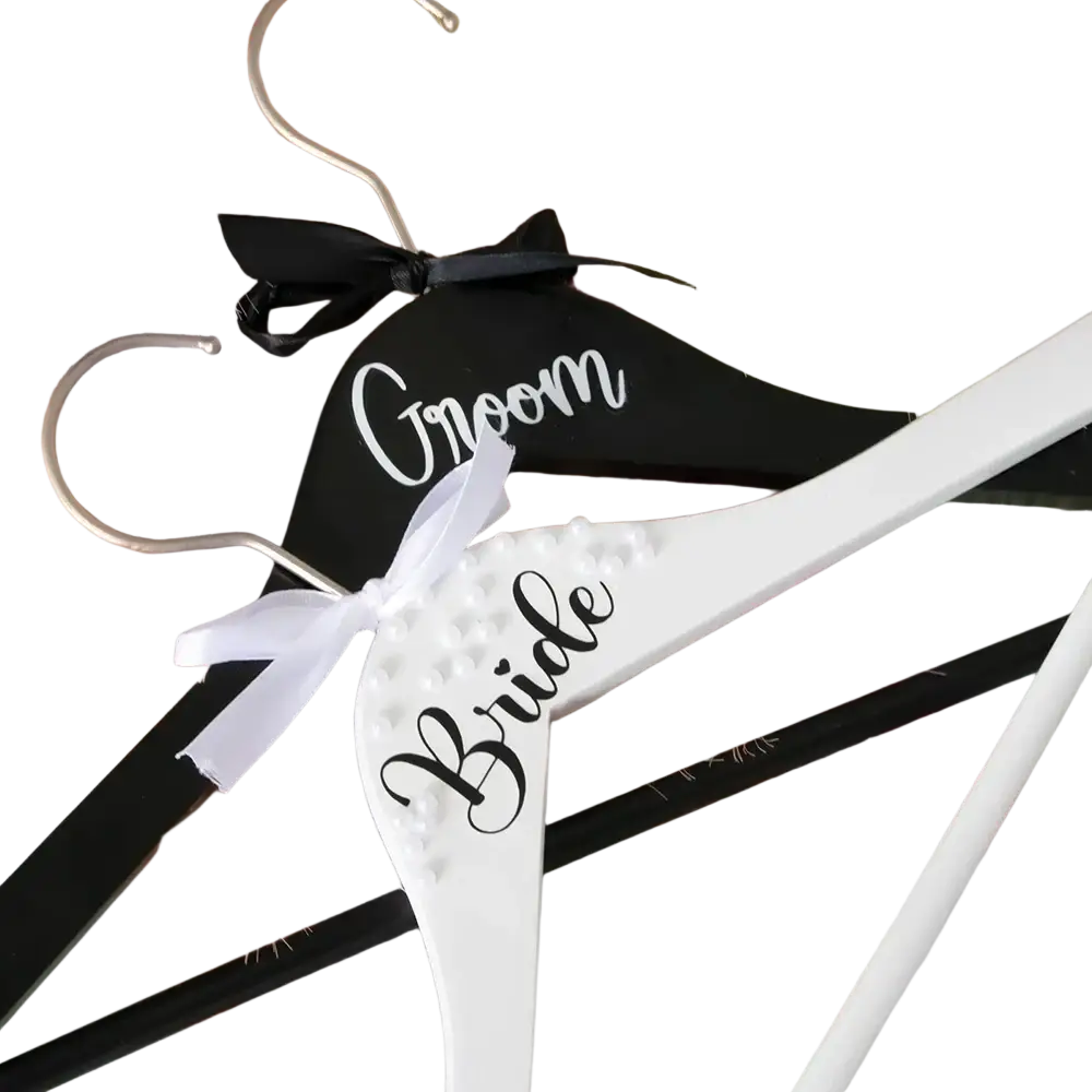 Black and white wooden bride and groom pearl wedding hangers set with labeled bows for bridal attire display