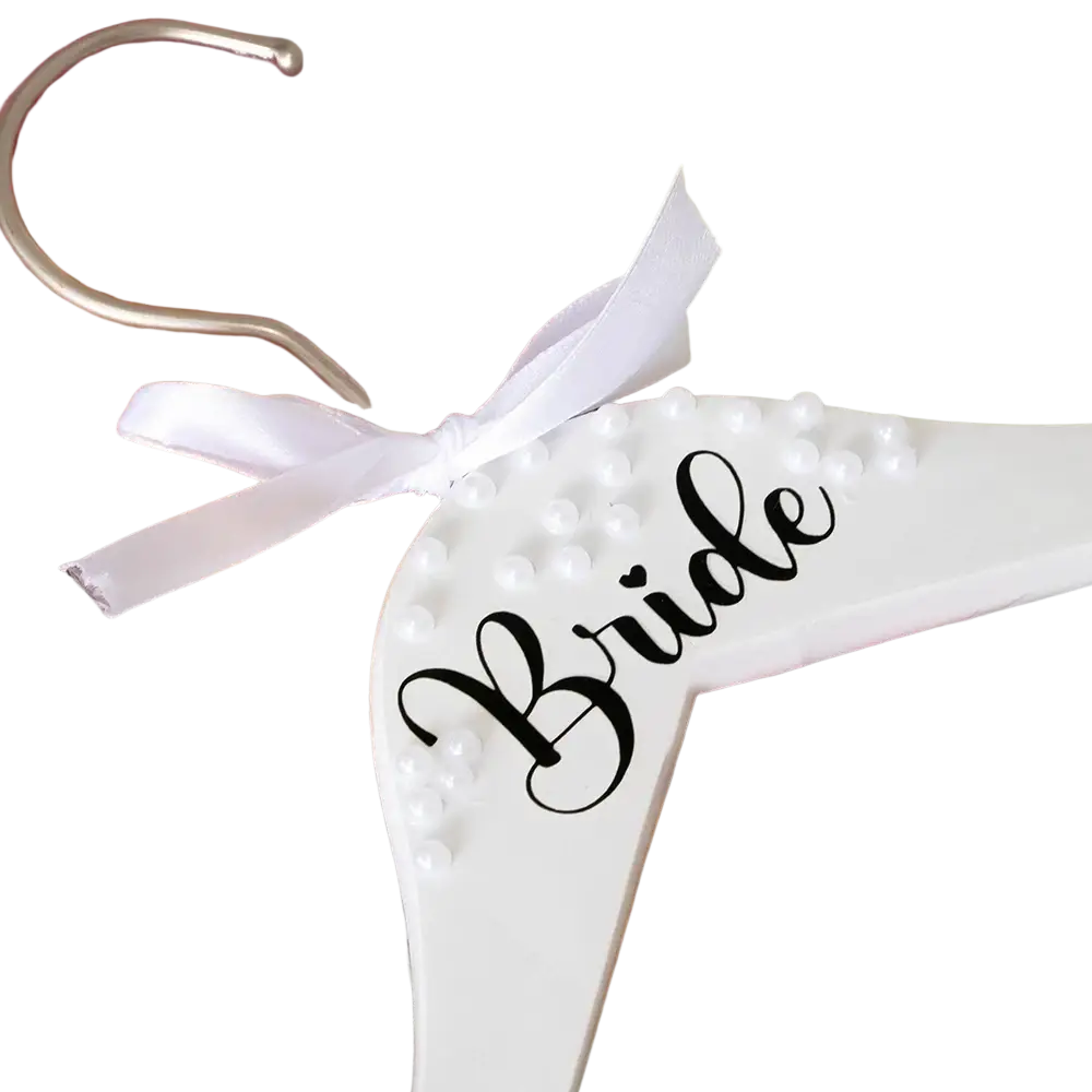 White wooden bride hanger adorned with pearls and black cursive lettering tied with white satin ribbon for weddings