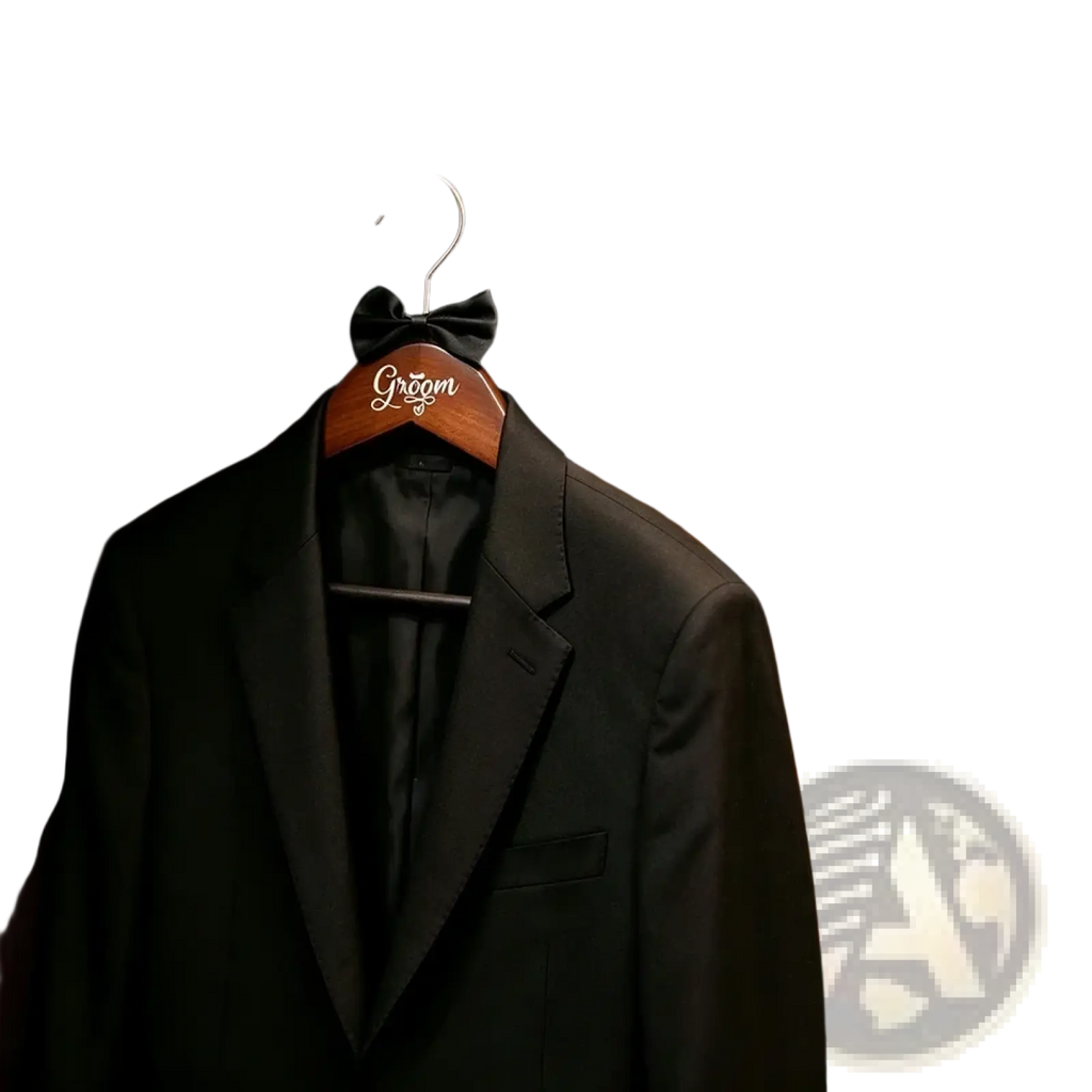 Black tuxedo jacket with black bow tie hanging on a bride and groom pearl wood wedding hanger engraved groom