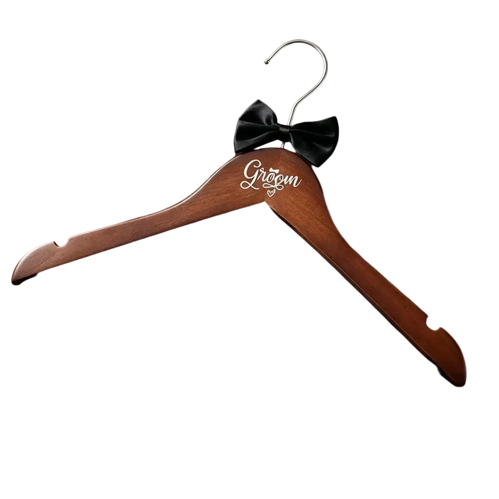 A polished wooden groom wedding hanger with silver hook, engraved inscription, and black satin bow from a pearl wood set