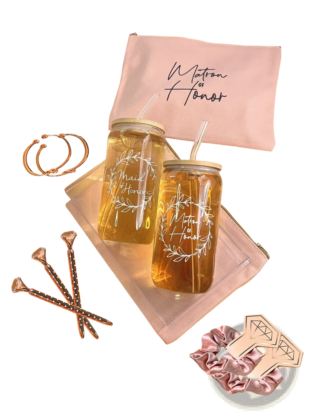 Two clear glass mason jar tumblers with gold lids and white maid of honor wreath designs filled with golden liquid