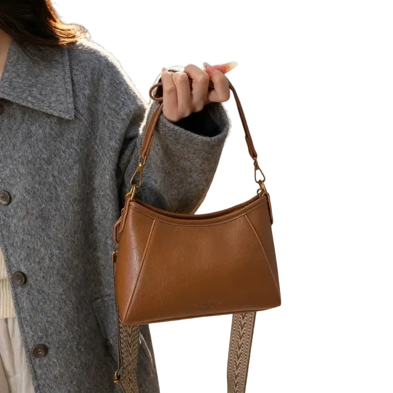 A tan leather brown crossbody shoulder bag for women with a structured angular design and gold tone hardware